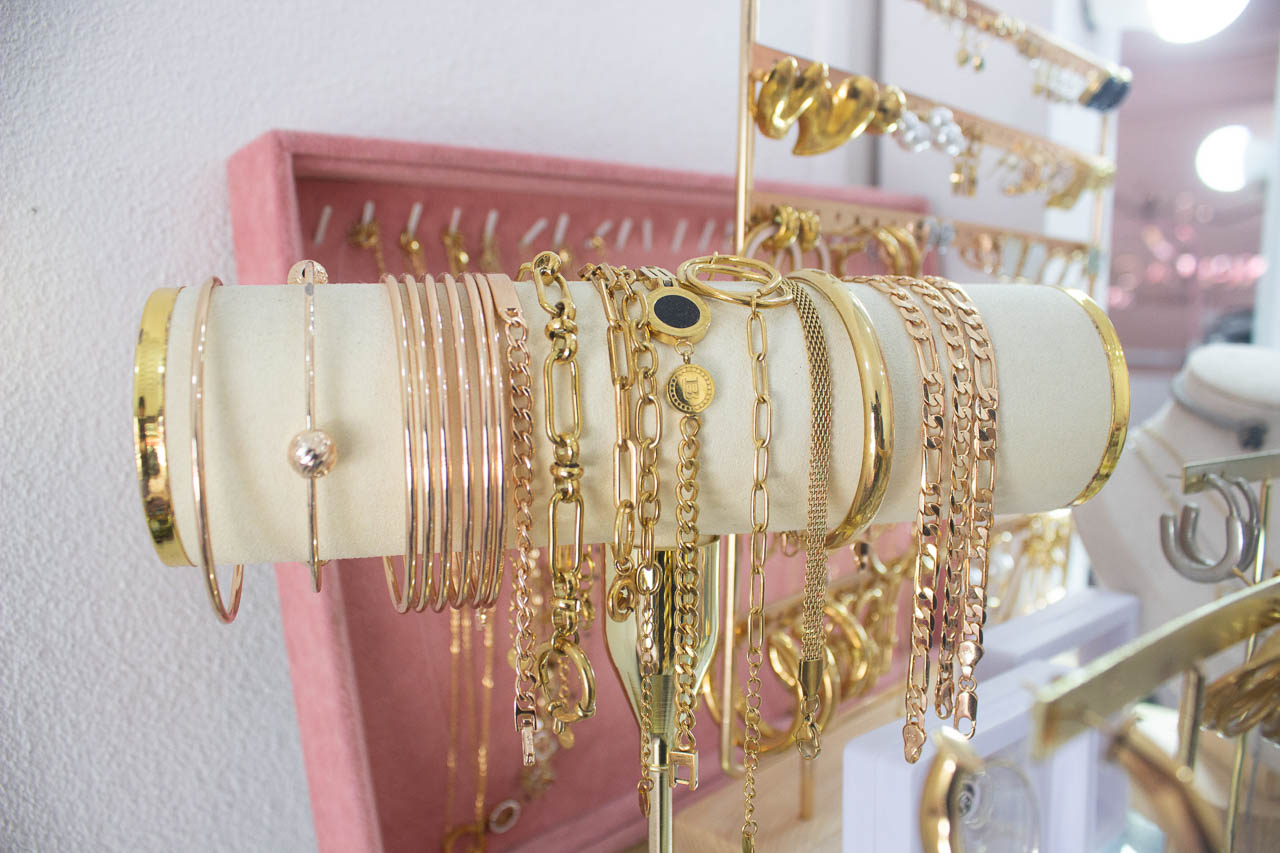 Exhibidor de pulseras y cadenas doradas en el área de accesorios del salón